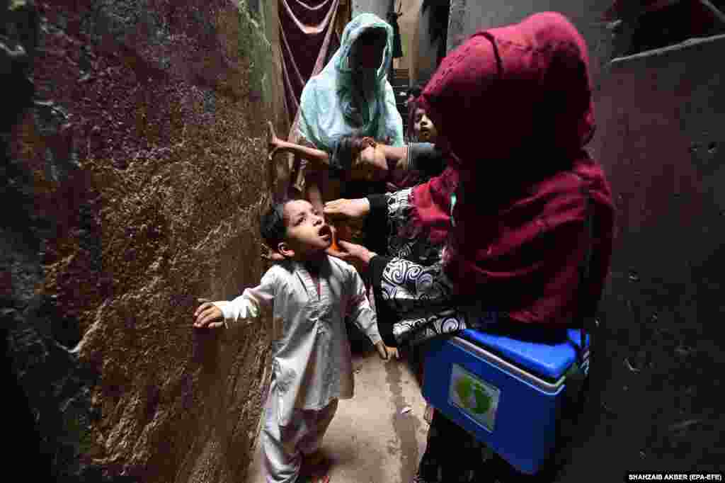 A health worker administers polio vaccine drops to a child during a door-to-door vaccination campaign in Karachi, Pakistan.