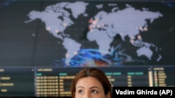 Një grua ulur në sfond të hartës botërore të sulmeve kibernetike në kohë reale në zyrat e Bitdefender në Bukuresht, Rumani, qershor 2017. 