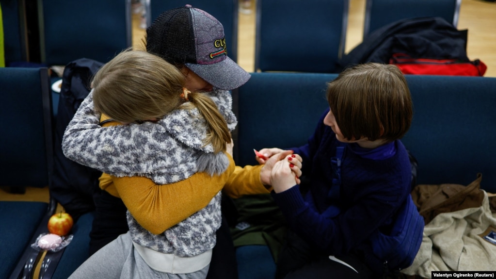 A woman holds her daughter and son, who went to a Russian-organized summer camp from nongovernment-controlled territories and were then taken to Russia, after they returned via Belarus in Kyiv in April.