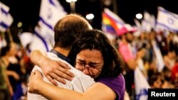 Një grua e trishtuar duke e përqafuar një burrë gjatë protestave në Izrael, pas votimit të reformave përçarëse.