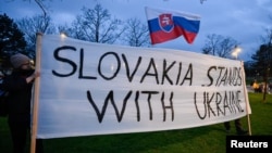 Хора държат плакат в солидарност с Украйна по време на протеста във вторник.