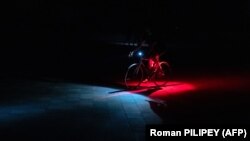Велосипедист їде неосвітленою вулицею в Києві під час відключень світла, 6 червня 2024 року