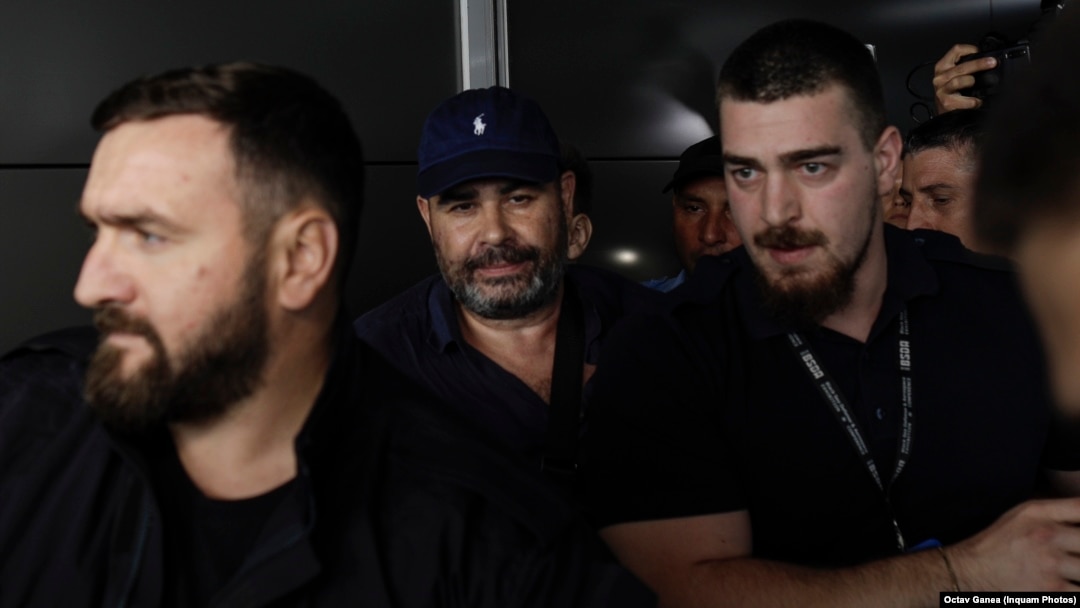 Fostul ministru Darius Vâlcov (centru) pe Aeroportul Otopeni, flancat de polițiști, în ziua în care a fost extrădat din Italia, 14 august 2023.