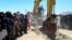 Taliban security personnel surround an excavator at work during an inauguration ceremony of the Mes Aynak copper-mining project on July 24.