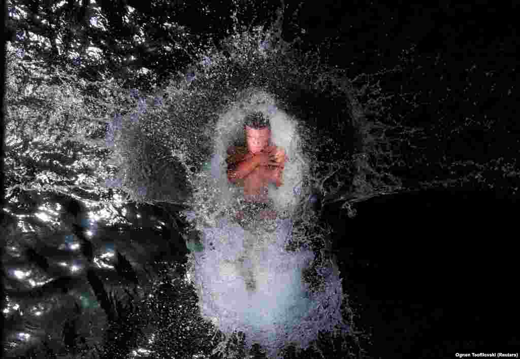 A boy jumps into the Treska River to cool off from the hot weather near Skopje, North Macedonia.