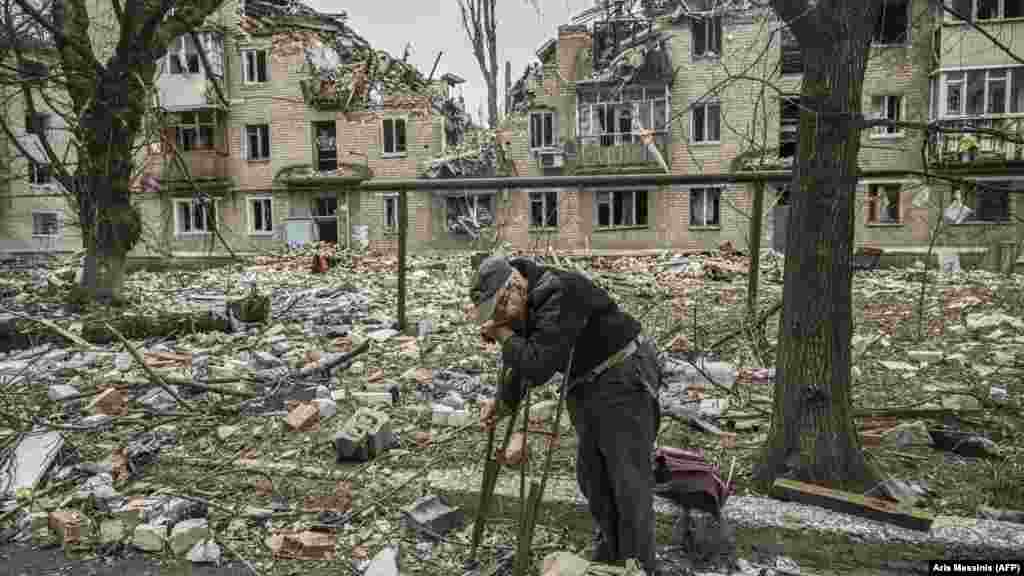 Stariji muškarac skuplja drva iz ruševina uništene stambene zgrade nakon napada u gradu Avdijevki, u oblasti Donjecka.