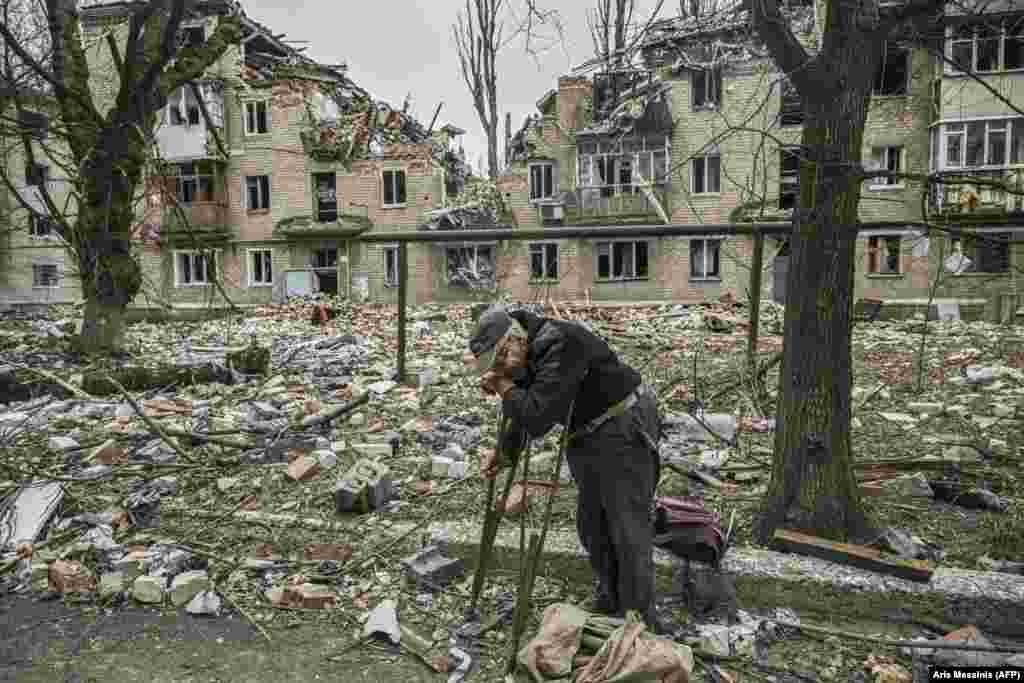 An elderly man collects wood from the debris of a destroyed apartment building after a strike in the city of Avdiyivka in Ukraine&#39;s eastern Donetsk region.