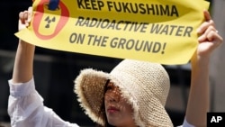 Учасниця протесту біля Токійської енергетичної компанії з вимогою до Японії відмовитися від свого плану скидати у море величезні запаси очищеної, але все ще радіоактивної води, травень 2023 року