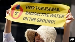 Një protestuese në Tokio mban një pankartë që shënon "Mbani ujin radioaktiv të Fukushimës në Tokë", 16 maj 2023. 