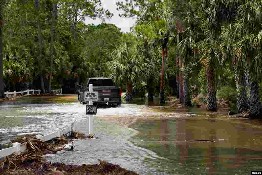 Një automjet duke lëvizur në një rrugë të përmbytur nga uragani Idalia në Cedar Key, Florida.