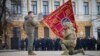 A Ukrainian Army officer kisses the flag of a military unit held by Ukrainian President Volodymyr Zelenskiy during a ceremony marking the anniversary of Russian's invasion, on February 24. 