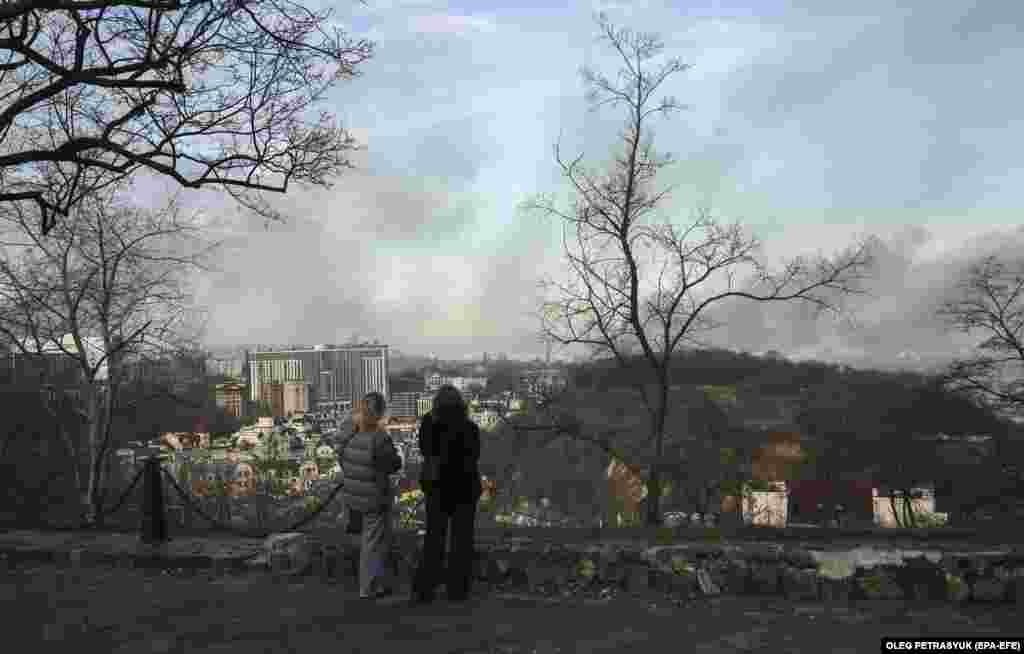 Women watch as smoke rises above the city of Kyiv following a Russian missile attack on December 29. Russian forces overnight carried out the &quot;largest air attack&quot; on Ukraine since the beginning of the war, the Ukrainian military&#39;s commander in chief, General Valeriy Zaluzhniy, said.