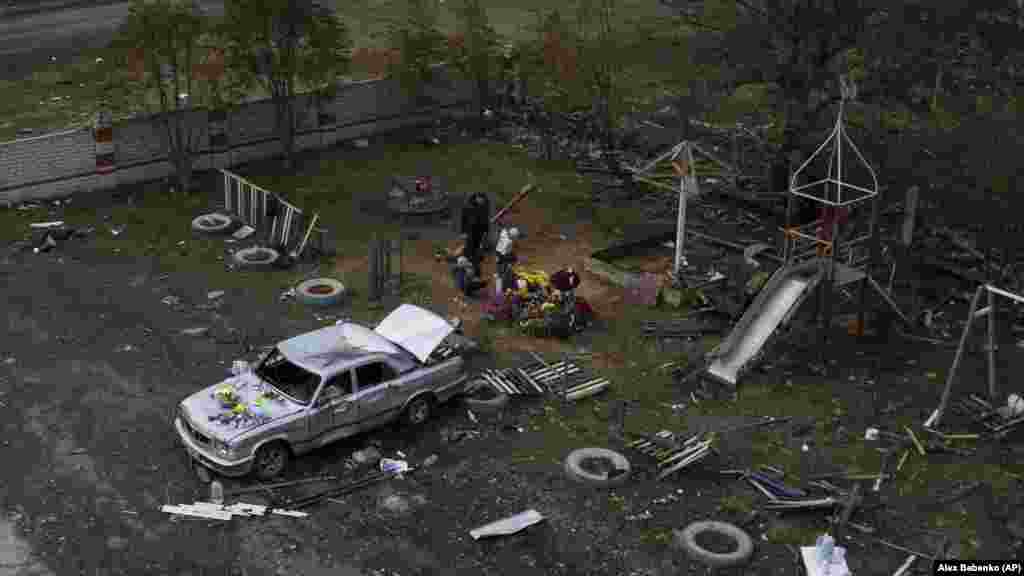 Family members leave flowers near a memorial for victims of a deadly Russian rocket attack in the village of Hroza near Kharkiv.