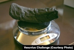Unul din pergamentele descoperite la Herculaneum, care au fost descifrate cu ajutorul inteligenței artificiale în cadrul competiției Vesuvius Challenge.
