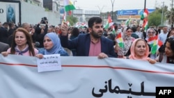 Okupljeni demonstranti mahali su zastavom iračkog Kurdistana i držali transparent na kojem su bombardiranje aerodroma nazvali "terorističkim činom", Sulejmanija, Irak, 9. aprila 2023.