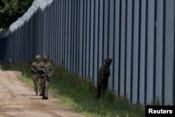 Польські солдати патрулюють вздовж паркану на польсько-білоруському кордоні в Уснаж-Ґурнах, Польща, 30 серпня 2023 року