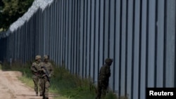 Polish soldiers patrol along the border fence on the Polish-Belarusian border in Usnarz Gorny.