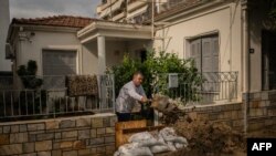  Местен гражданин почиства входа на къщата си след бурята 