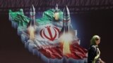 Ирандык аял Тегерандагы Израилге каршы маанайдагы жарнактын жанынан өтүп баратат. 19-апрель, 2024-жыл.
