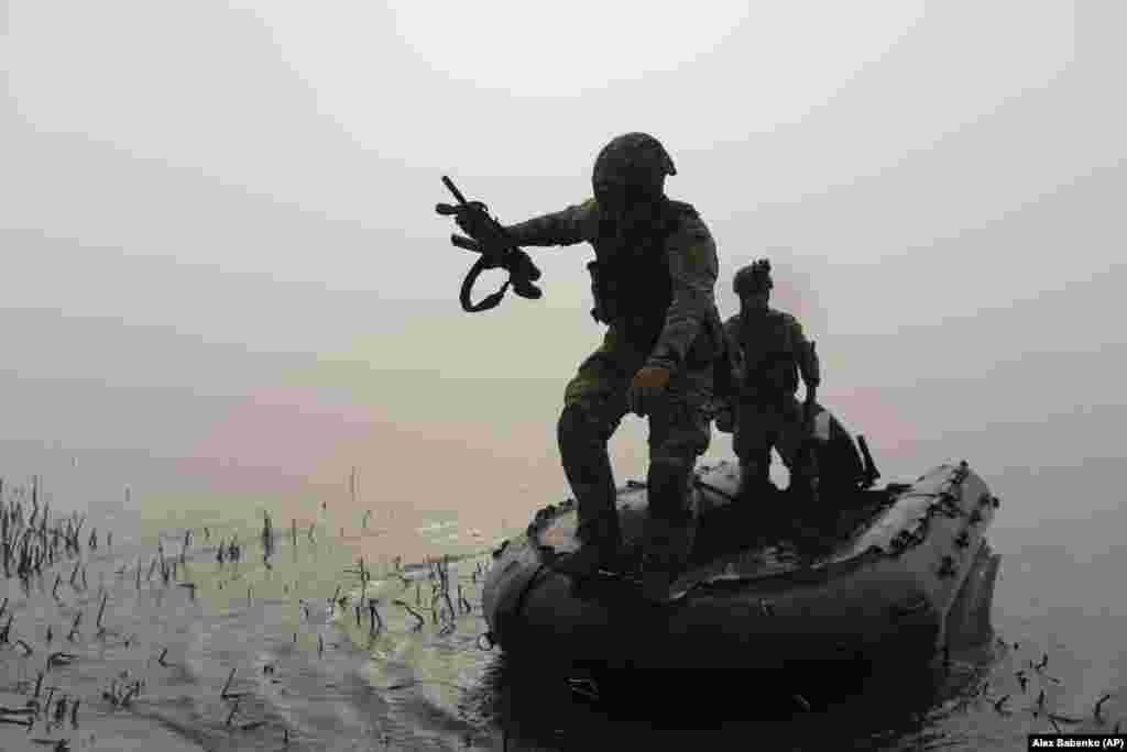 A Ukrainian soldier jumps out of a boat onto the bank of the Dnieper River at the front line near Kherson in southern Ukraine.