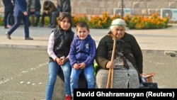Nagorno-Karabakh - An elderly woman and children sit on bags of belongings as residents gather in central Stepanakert to leave Nagorno-Karabakh, September 25, 2023.