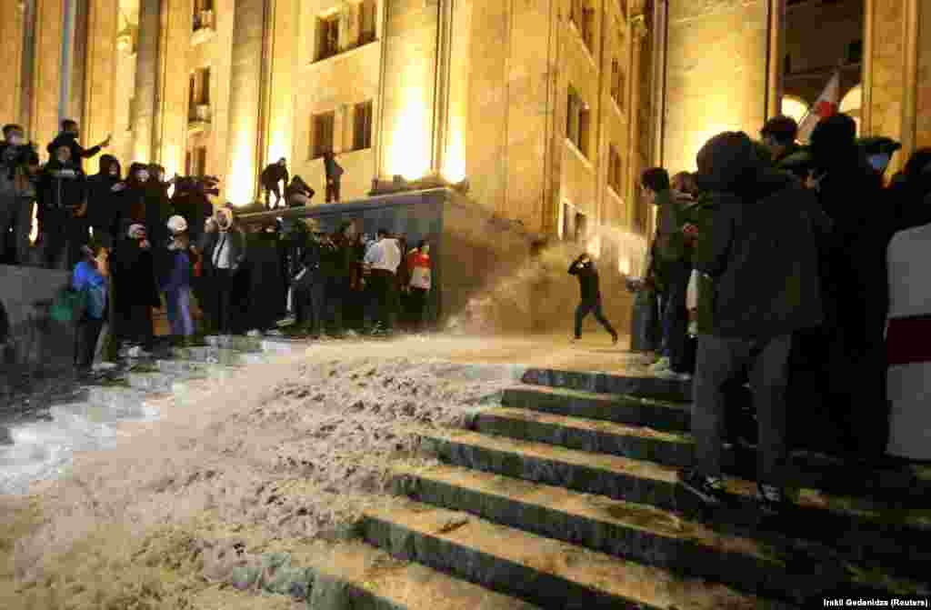 По сходах грузинського парламенту стікає вода. На відео з протестів у Тбілісі видно, як поліція всередині будівлі поливала протестувальників водою, змішаною зі сльозогінним газом, коли натовп намагався штурмувати будівлю законодавчого органу Грузії
