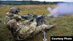 Two soldiers fire an M-249 light machine gun at an unknown location.