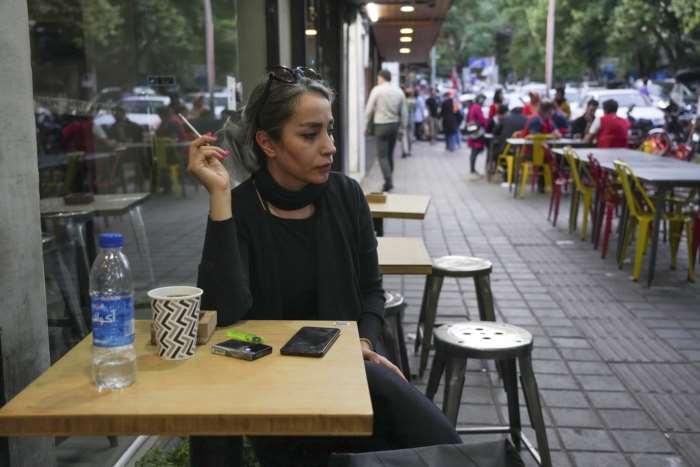 A woman sits in the alfresco dining area of a cafe in the Tajrish commercial district in northern Tehran without wearing her mandatory Islamic head scarf on April 29, 2023.