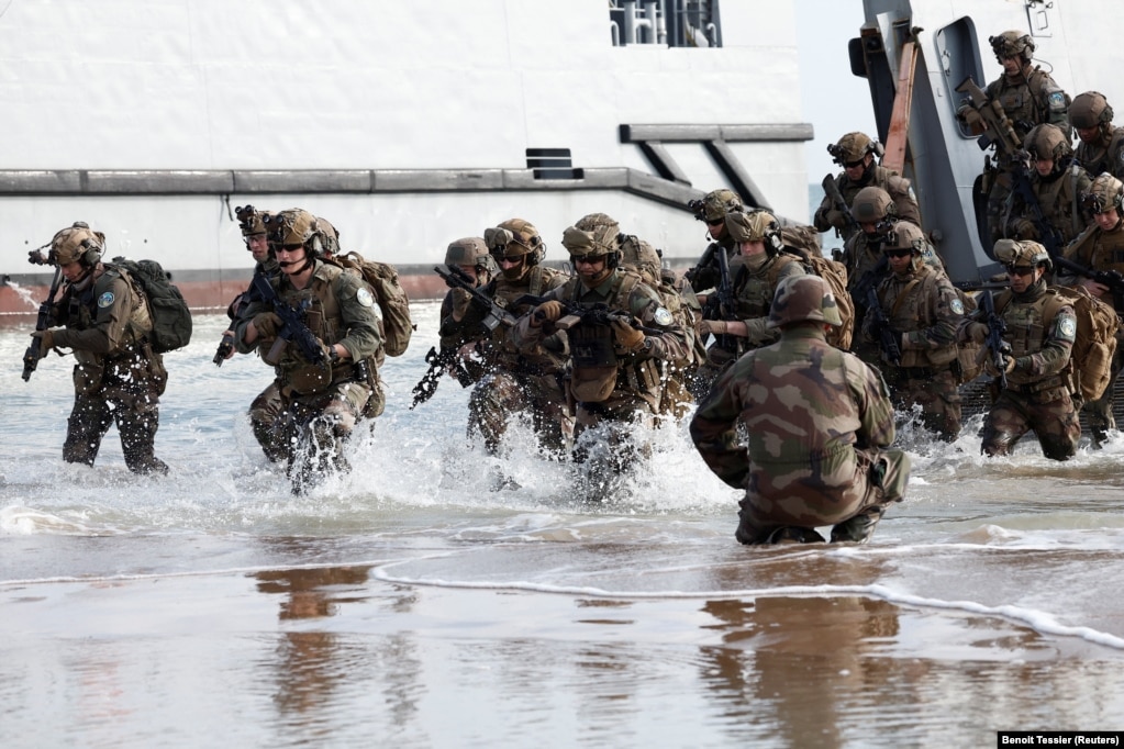 Trupat franceze duke zbarkuar nga një mjet fluturues amerikan që tregon një ulje amfibe në plazhin Omaha më 4 qershor para ceremonive për 80-vjetorin e Ditës D në Saint-Laurent-sur-Mer. Stërvitja u mbajt në një kohë kur presidenti francez, Emmanuel Macron, po shqyrton dërgimin e instruktorëve ushtarakë nga vendi i tij në Ukrainë.