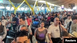 Pasagerii așteaptă la Aeroportul Barajas din Madrid, în timp ce operatorul spaniol de aeroporturi a anunțat un „incident” informatic la toate aeroporturile spaniole care ar putea cauza întârzieri ale zborurilor. 19 iulie 2024