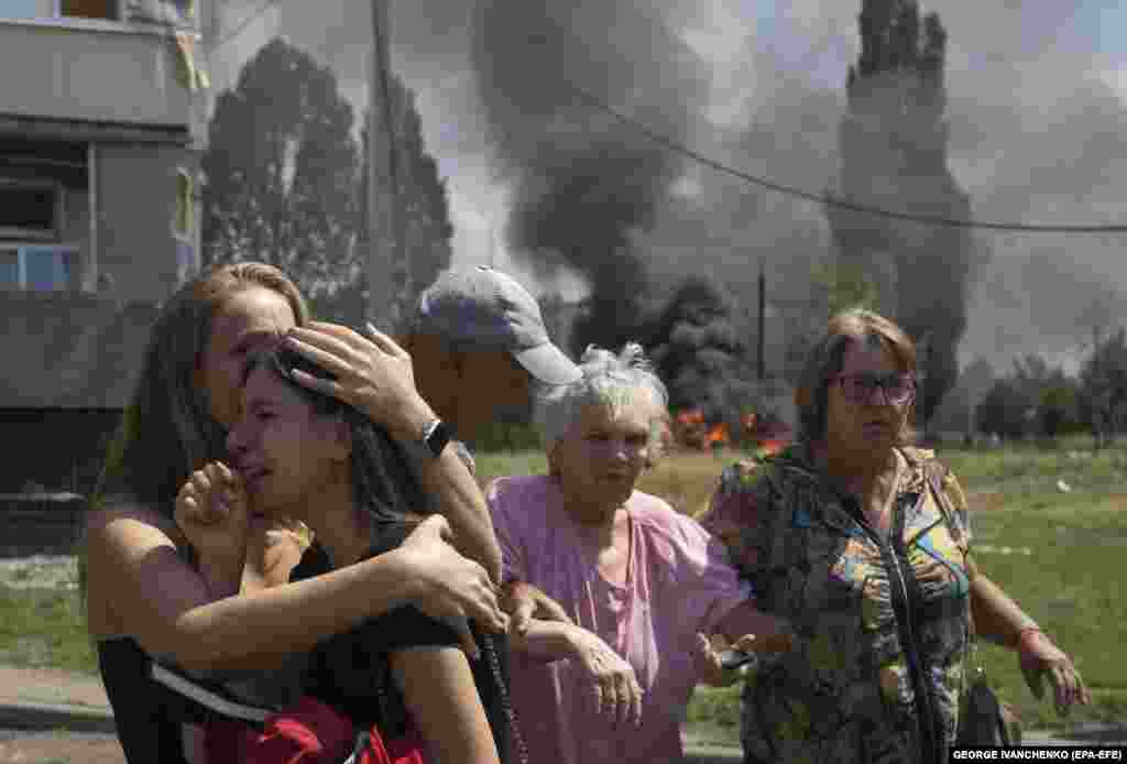 Locals react at the scene of a rocket attack on the Pervomayskiy settlement in the Kharkiv region of eastern Ukraine on July 4. At least 31 people were injured, including nine children, according to the State Emergency Service.