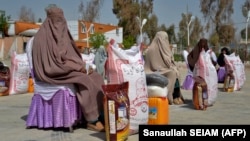 Afghan women sit after receiving food aid distributed by a charity foundation during the Muslim holy fasting month of Ramadan in Kandahar on March 28.