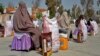 Afghan women sit after receiving food aid distributed by a charity foundation in Kandahar on March 28.