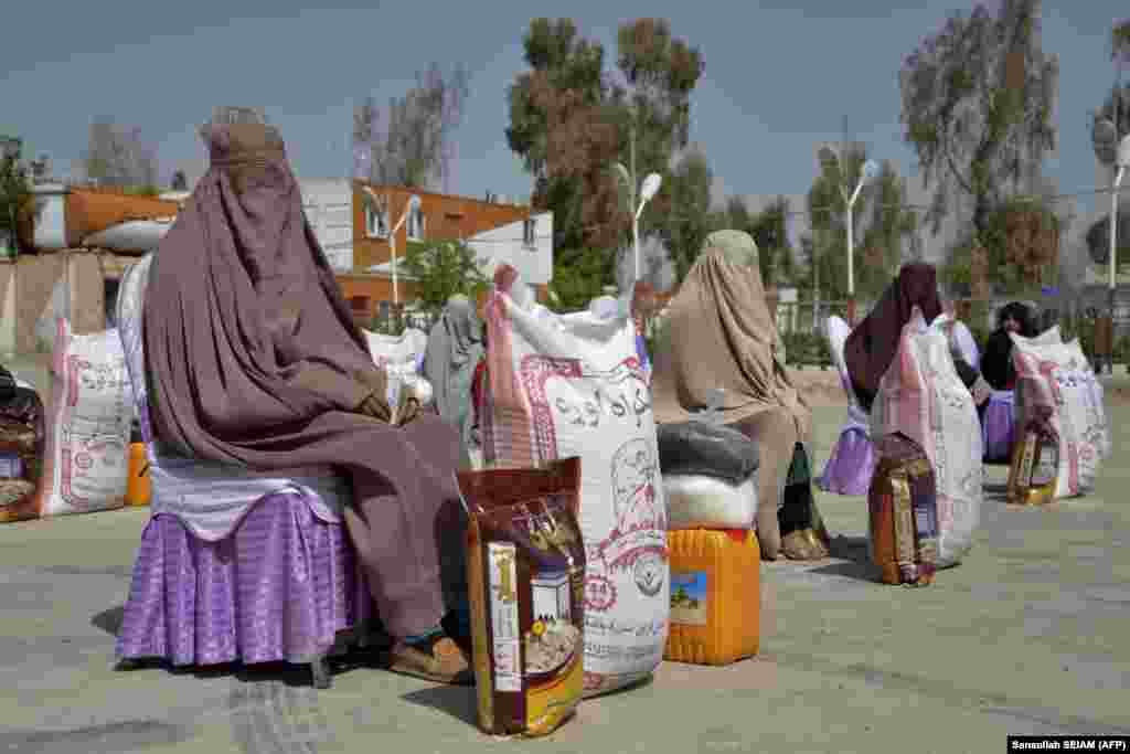 Afghan women sit after receiving food aid distributed by a charity foundation during the Muslim holy fasting month of Ramadan in Kandahar.