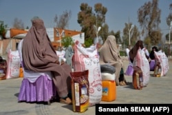 Afghan women sit after receiving food aid distributed by a charity foundation during the Muslim holy fasting month of Ramadan in Kandahar. (file photo)