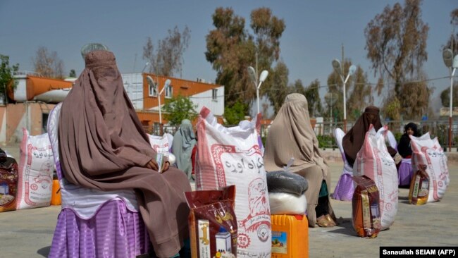 Gratë afgane ulen pasi kanë marrë ndihma ushqimore të shpërndara nga një fondacion bamirësie gjatë muajit të shenjtë mysliman, Ramazanit, në Kandahar (Fotografi nga arkivi).