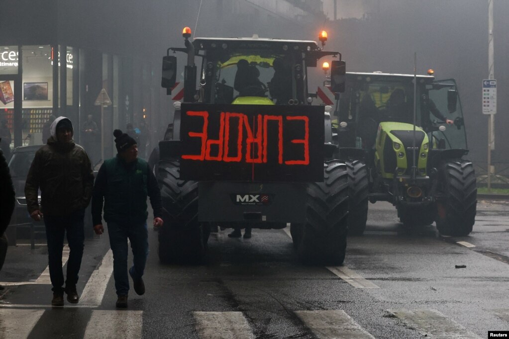 Njerëzit duke kaluar pranë një traktori gjatë protestës së fermerëve në Bruksel, më 26 shkurt 2024.