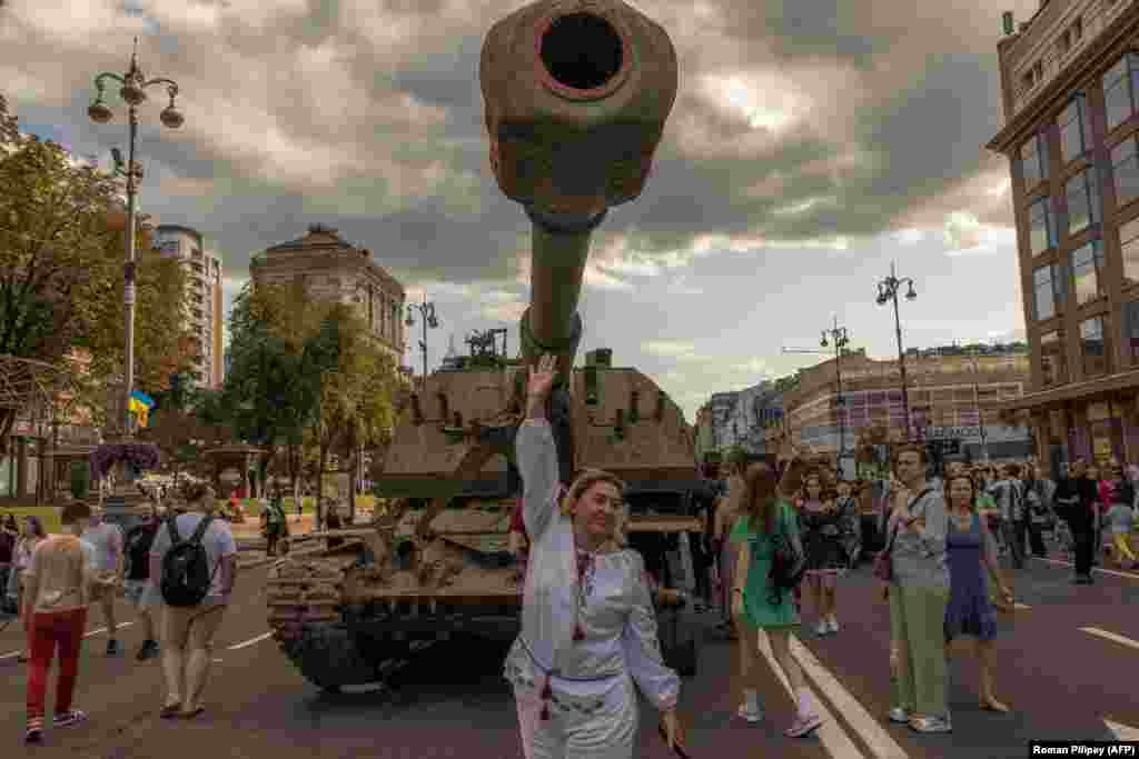 Një grua e veshur me rroba tradicionale ukrainase duke pozuar për fotografi para një automjeti ushtarak rus të blinduar të shkatërruar, i cili është ekspozuar në qendër të Kievit më 24 gusht, n Ditën e Pavarësisë së Ukrainës.