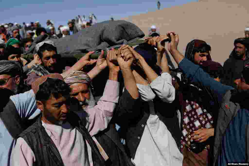 Afghan men carry the body of a woman on October 9 in the district of Zindah Jan. The epicenter of the October 7 quake -- also with a 6.3 magnitude -- was about 40 kilometers northwest of the provincial capital, Herat city. Sources at the local hospital in Herat told RFE/RL that at least one person was killed and 65 others were injured in the new earthquake.&nbsp;