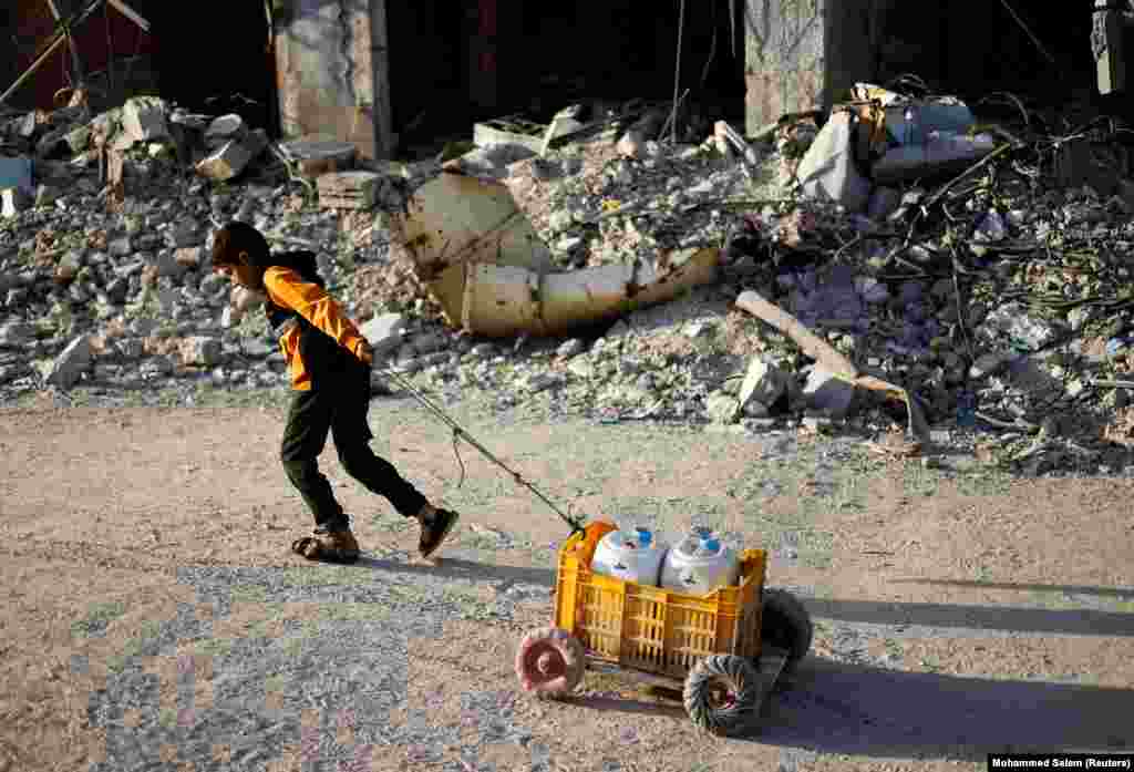 Një fëmijë palestinez tërheq një karrocë të improvizuar ku ka vendosur dy shishe me ujë. 