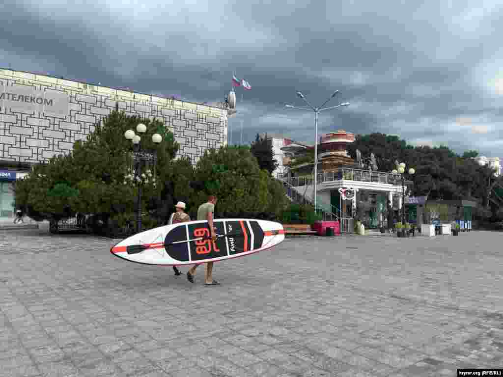 A paddleboarder heads to the beach under dark skies.&nbsp; The diamond-shaped peninsula, which was once a favorite vacation spot for Russian czars and hosted historic summits of world leaders, is struggling to attract tourists to its beaches.