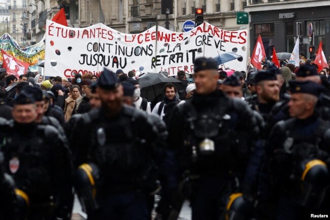 Policija hoda ispred demonstranata koji protestuju zbog penzione reforme u Francuskoj, Pariz, 14. april 2023.