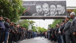 گروهی از هواداران حکومتی در تبریز زیر تابلوی کشته‌شدگان سانحه سقوط بالگرد رئیسی ایستاده‌اند