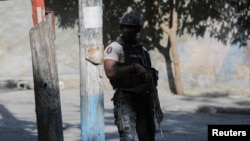 Policajac čuva stražu u blizini mjesta gdje je navodne članove bande zapalila gomila ljudi, u Port-au-Princeu, Haiti, 24. aprila 2023. 