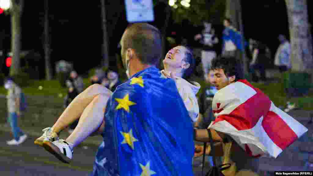 A man draped in an EU flag carries an injured protester. Supporters of the bill say it mirrors similar U.S. legislation and promotes transparency. Opponents say the proposed legislation would stifle dissent and silence independent media. They have compared it to similar legislation in Russia, which is why many call it the &quot;Russian law.&quot;&nbsp;