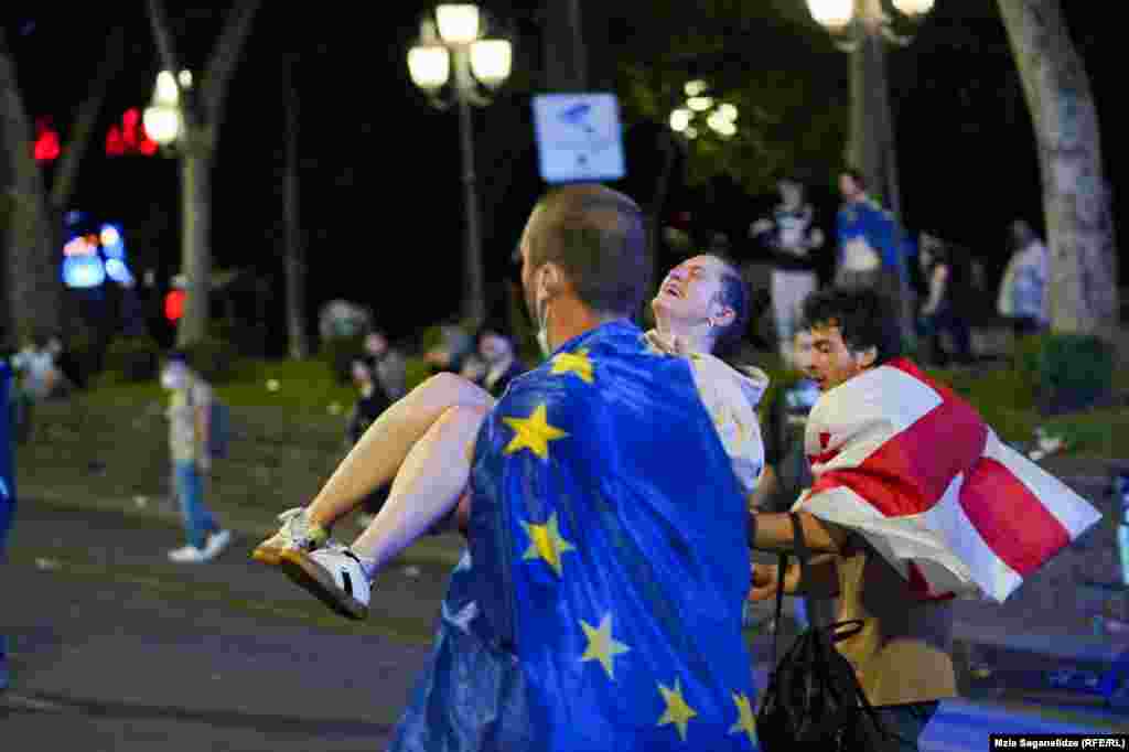 A man draped in an EU flag carries an injured protester as street protests in Tbilisi turned into a reportedly violent confrontation between police and demonstrators.