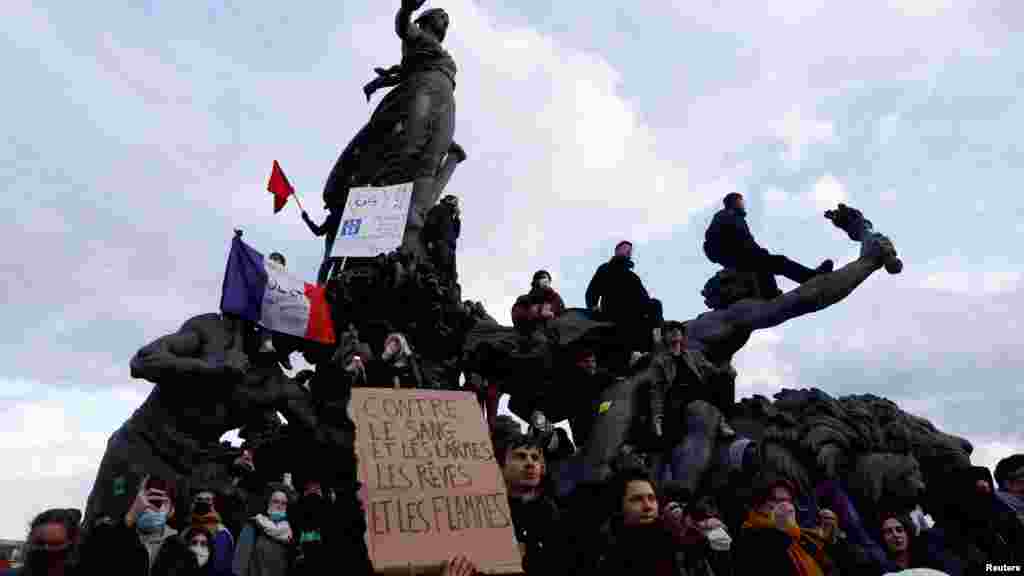 &bdquo;Álmok és lángok a vér és könny ellen&rdquo; &ndash; olvasható a demonstrálók tábláján, miközben többen is felmásztak a Place de la Nationon álló szoborcsoportra