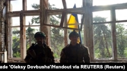 Soldații ucraineni stau în fața unui steag ucrainean pe care l-au ridicat într-un loc indicat drept satul Blagodatne, din regiunea Donețk, pe care Kievul a pretins că l-a eliberat pe 11 iunie.