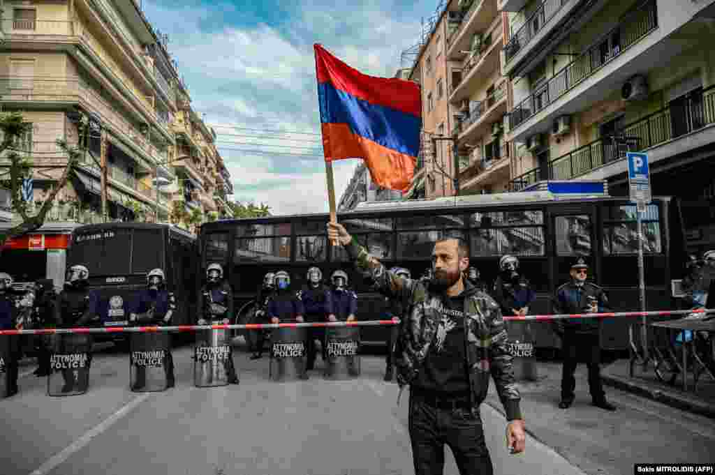 A man holds an Armenian flag in front of anti-riot police during a rally outside the Turkish consulate to commemorate the 108th anniversary of the Armenian genocide, in Thessaloniki on April 24.