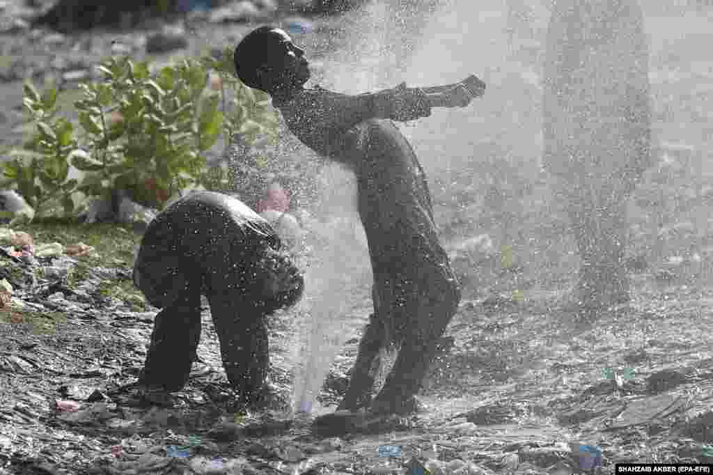 Children cool off at a water supply line as temperatures rise in Karachi, Pakistan.